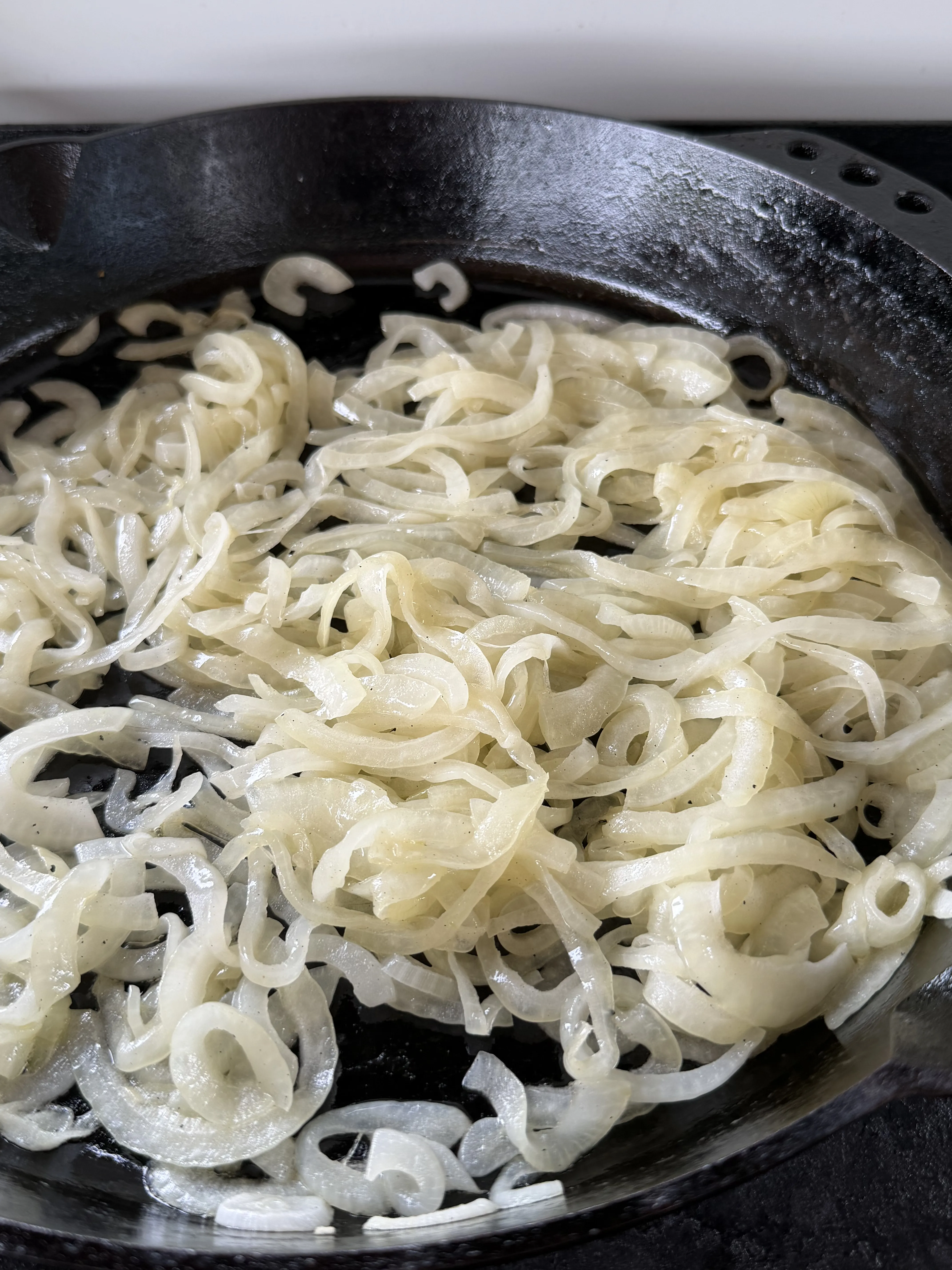 Sliced onions softening in a cast iron skillet on the way to caramelized