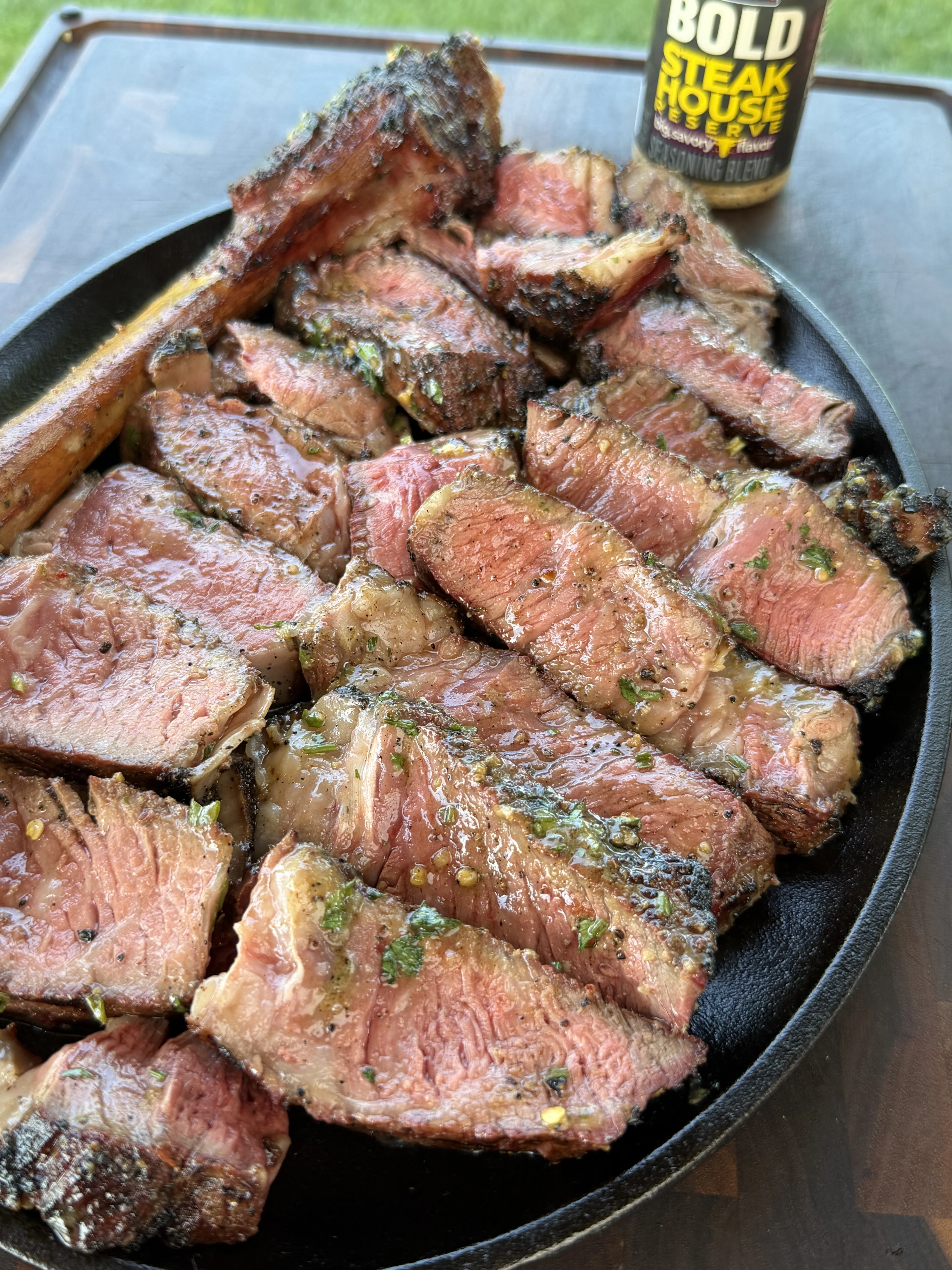 Rounds of compound butter melting over sliced steak in a cast iron skillet