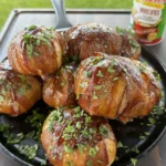 Smoked bacon cheeseburger onion bombs in a cast iron skillet, garnished with fresh parsley, with Tony Chachere's seasoning nearby
