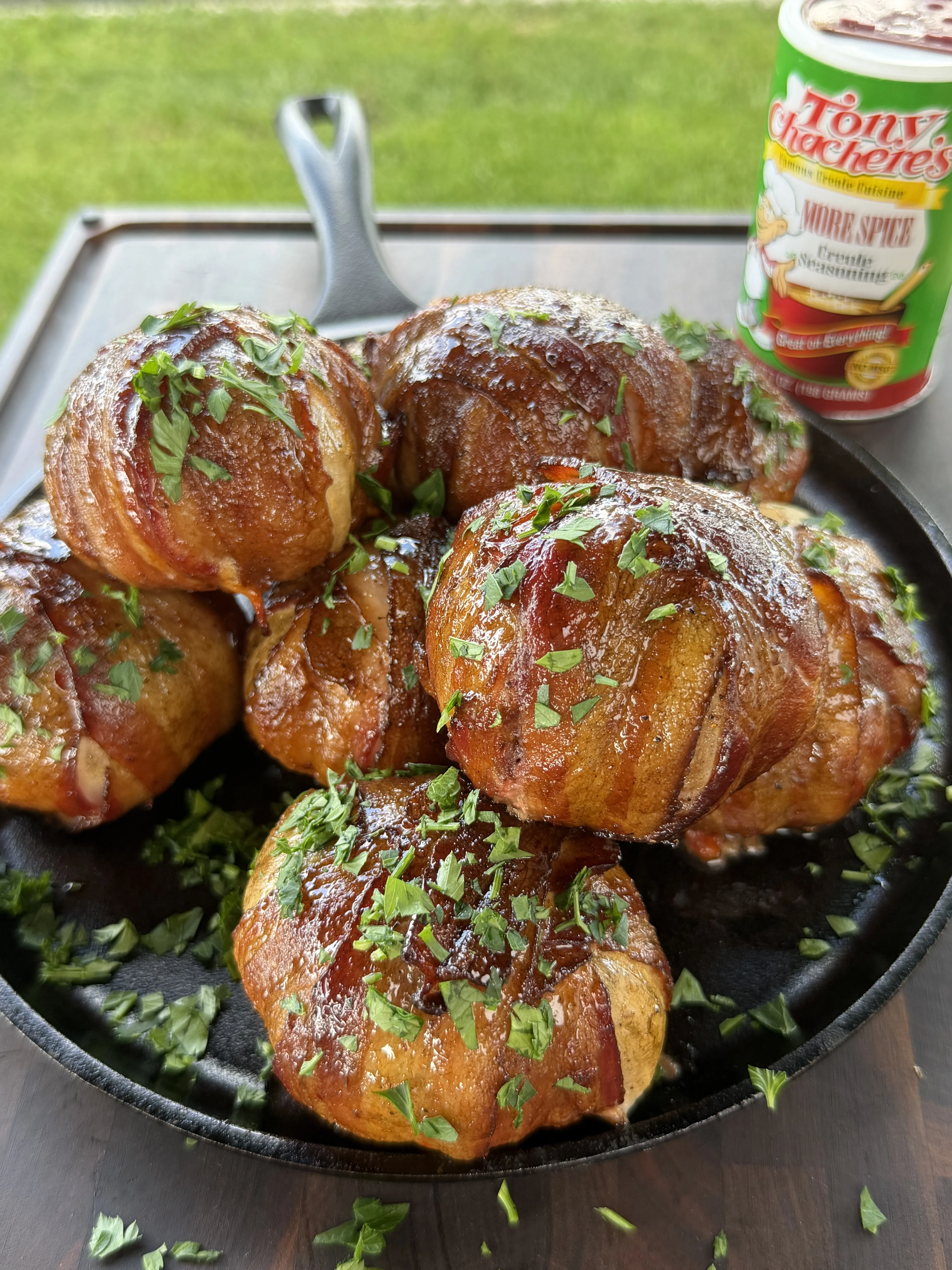 Smoked onion bombs stuffed with cheeseburger filling resting in a cast iron skillet with parsley
