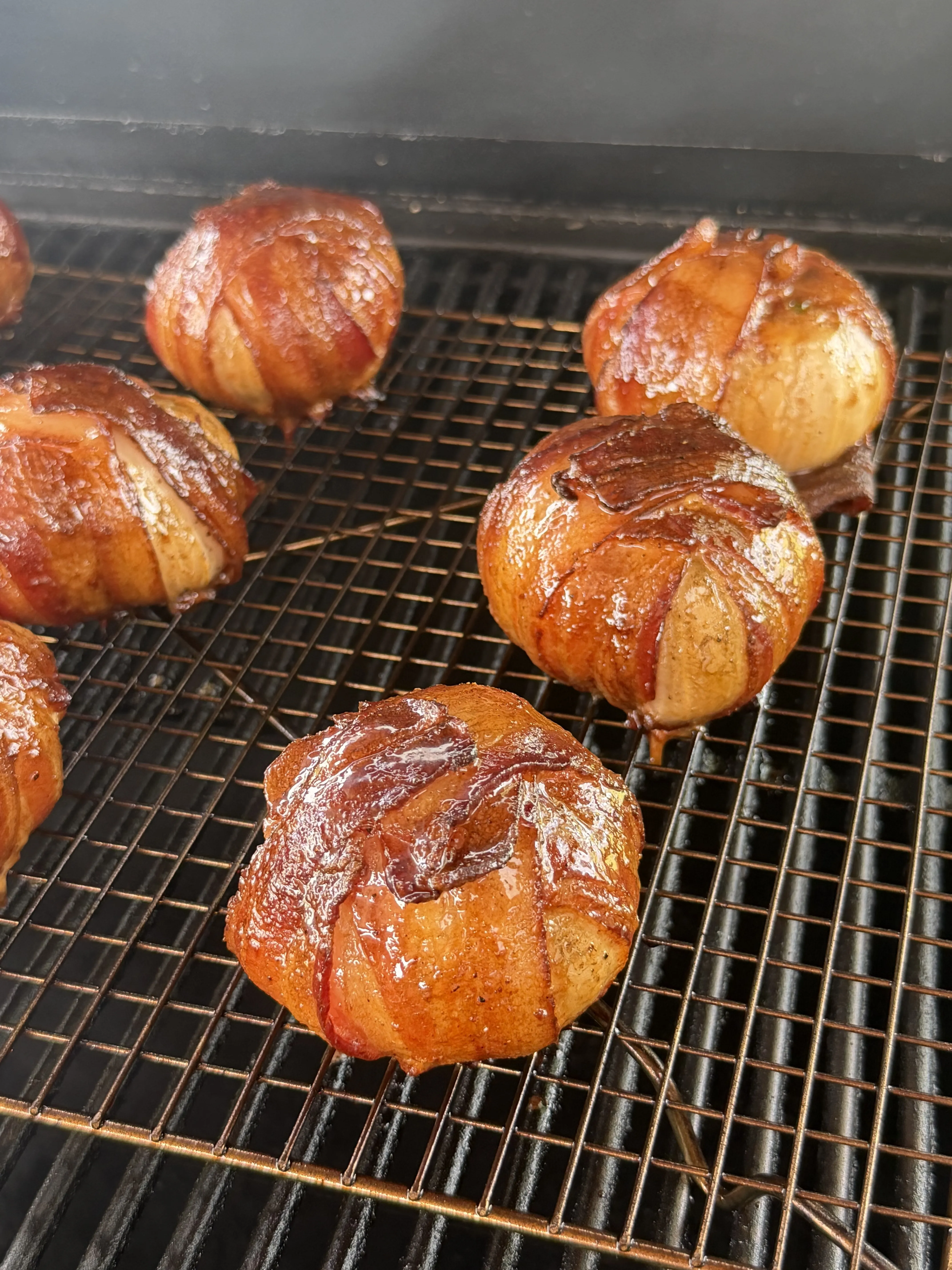Golden-brown glazed onion bombs finishing on grill grates