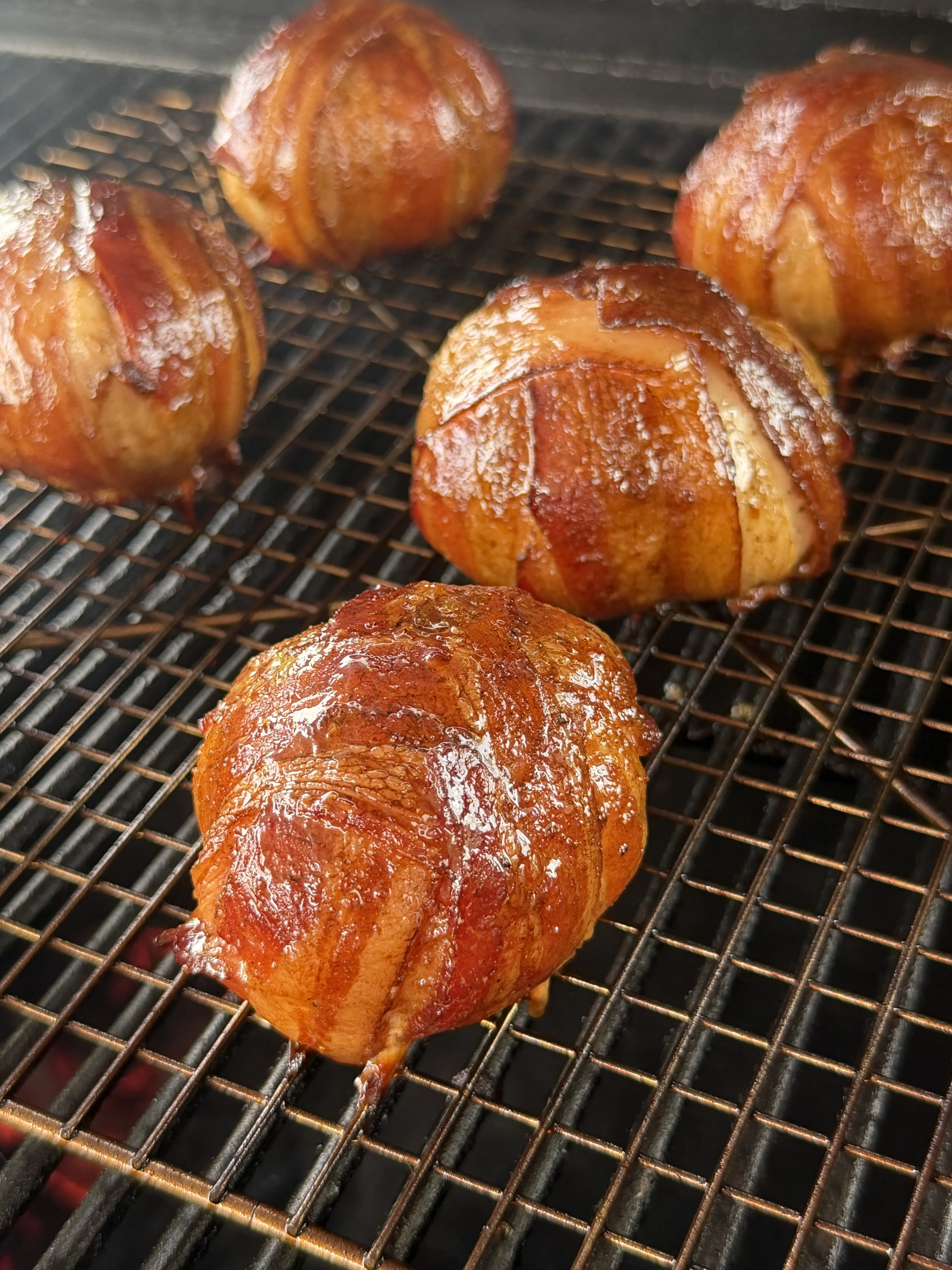 Glazed onion bombs caramelizing on a wire rack over the smoker fire