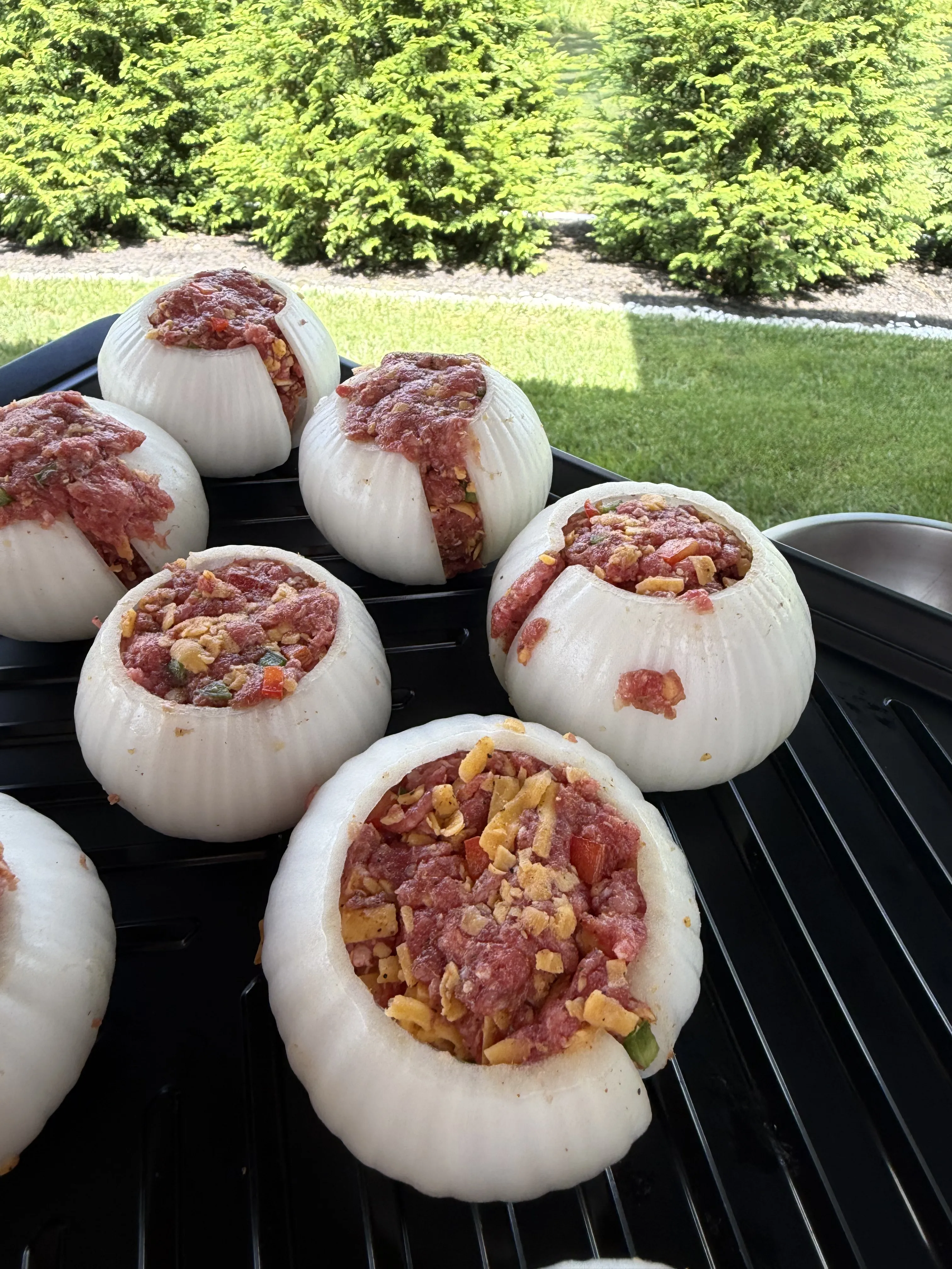 Onion bowls stuffed and mounded with raw cheeseburger filling