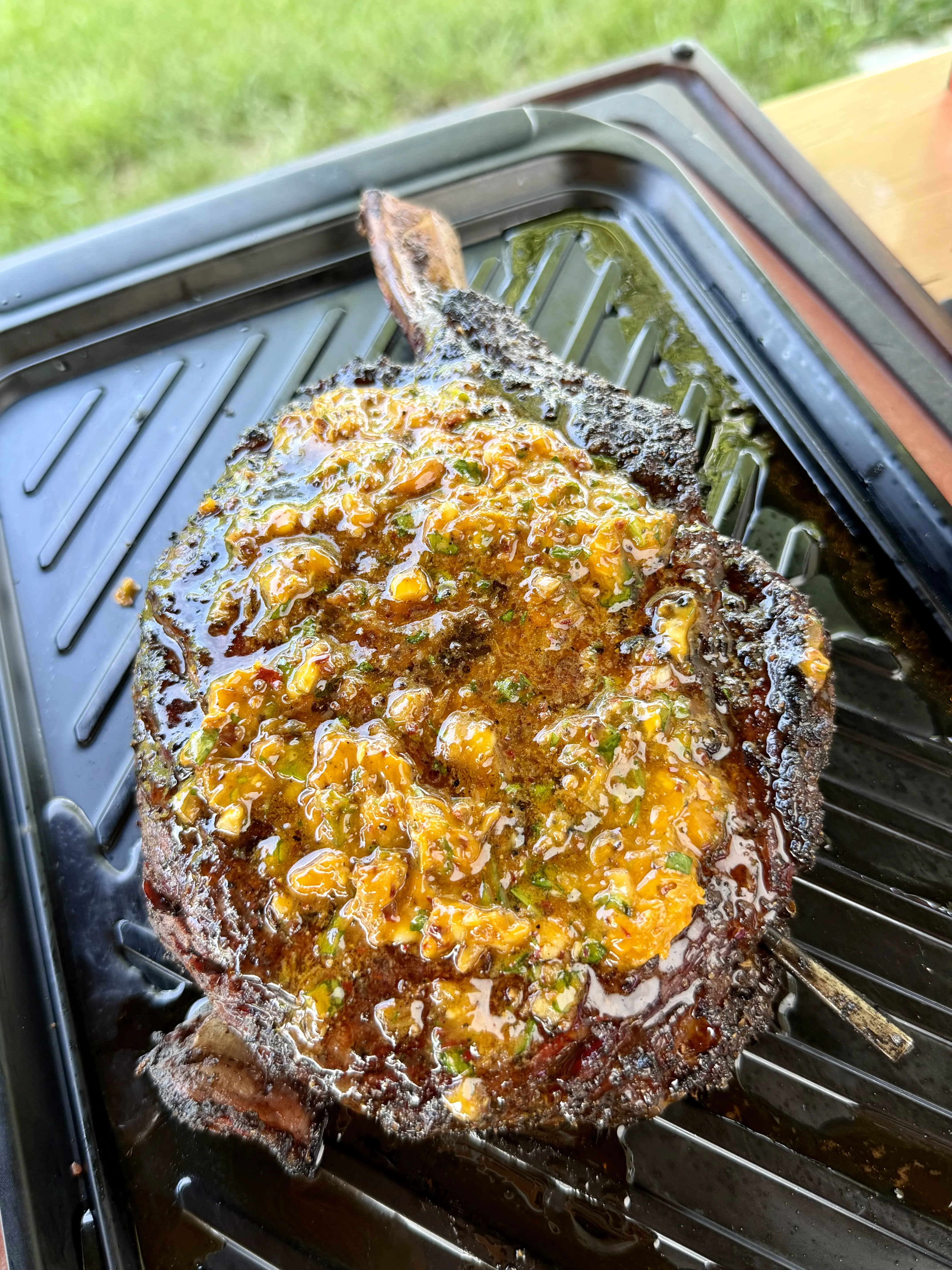 Tomahawk ribeye topped with crispy chili parmesan butter melting on the grill grate