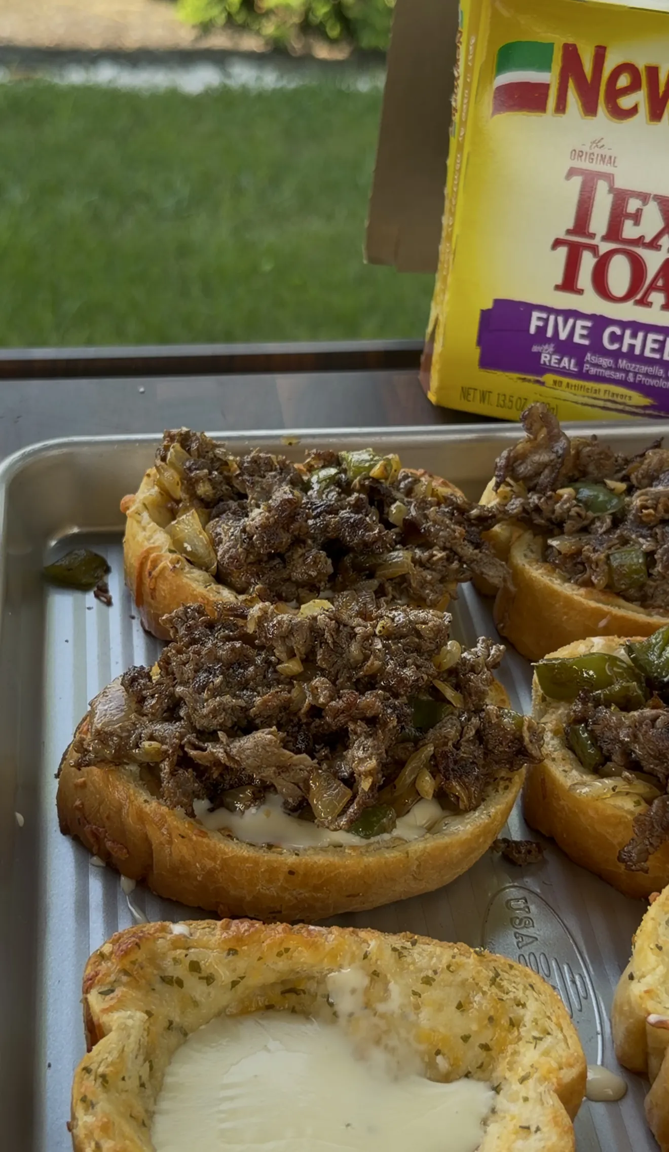 Open-face Cheesesteak Texas Toast with shaved steak, peppers, onions, and melted cheese