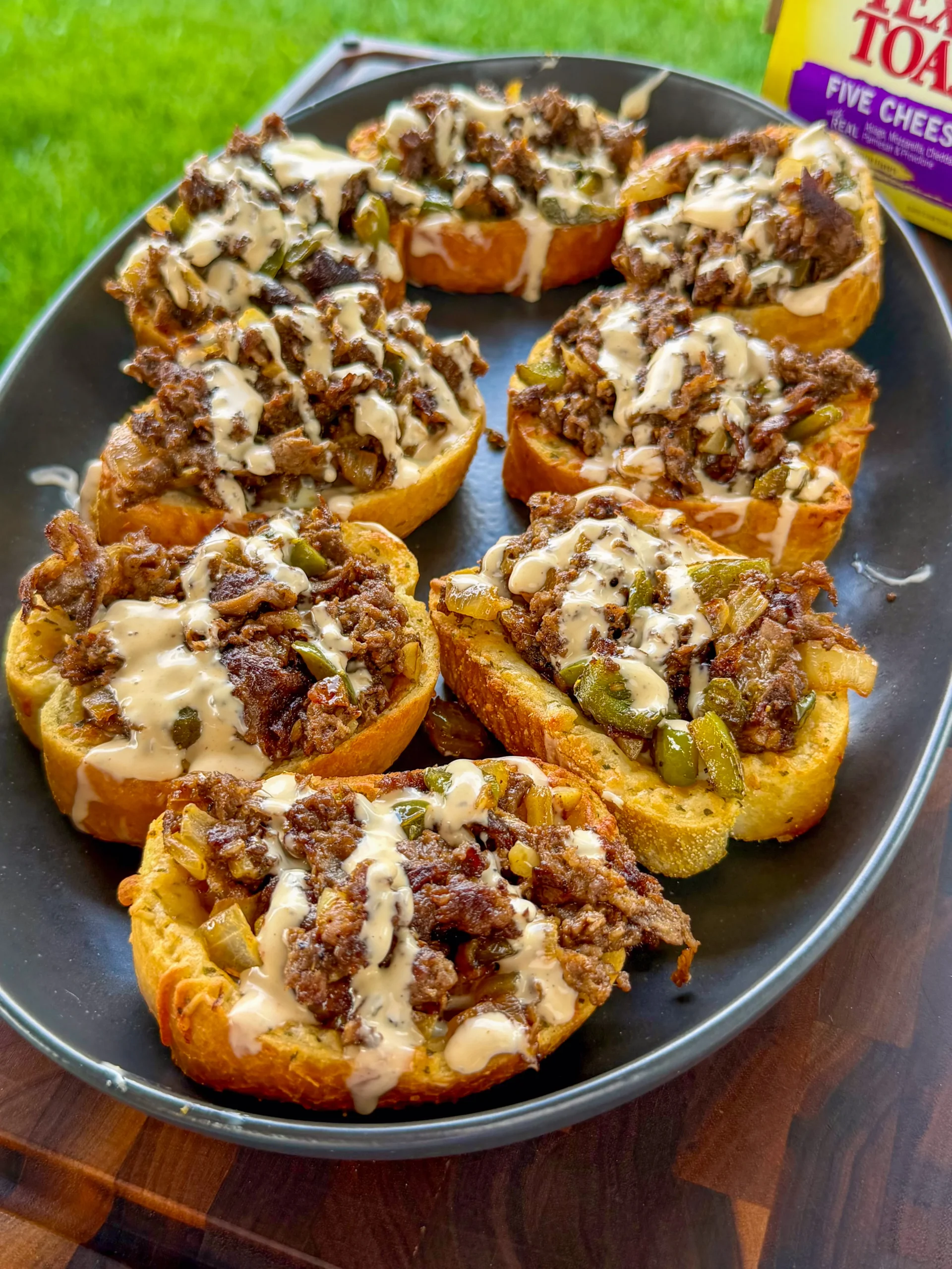 Open-face Cheesesteak Texas Toast with shaved steak, peppers, onions, and melted cheese