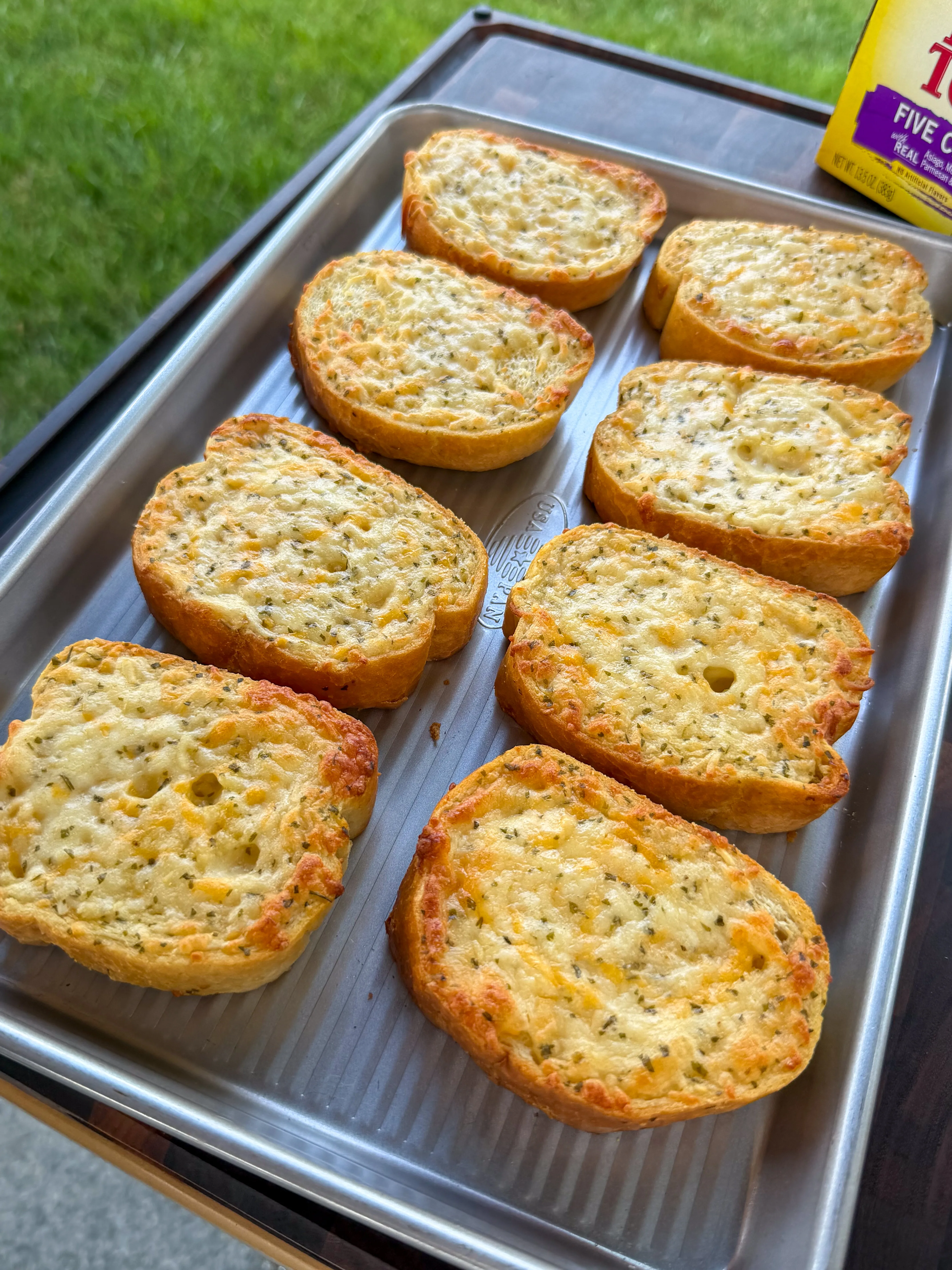 Eight slices of golden cheesy garlic Texas toast on a baking sheet