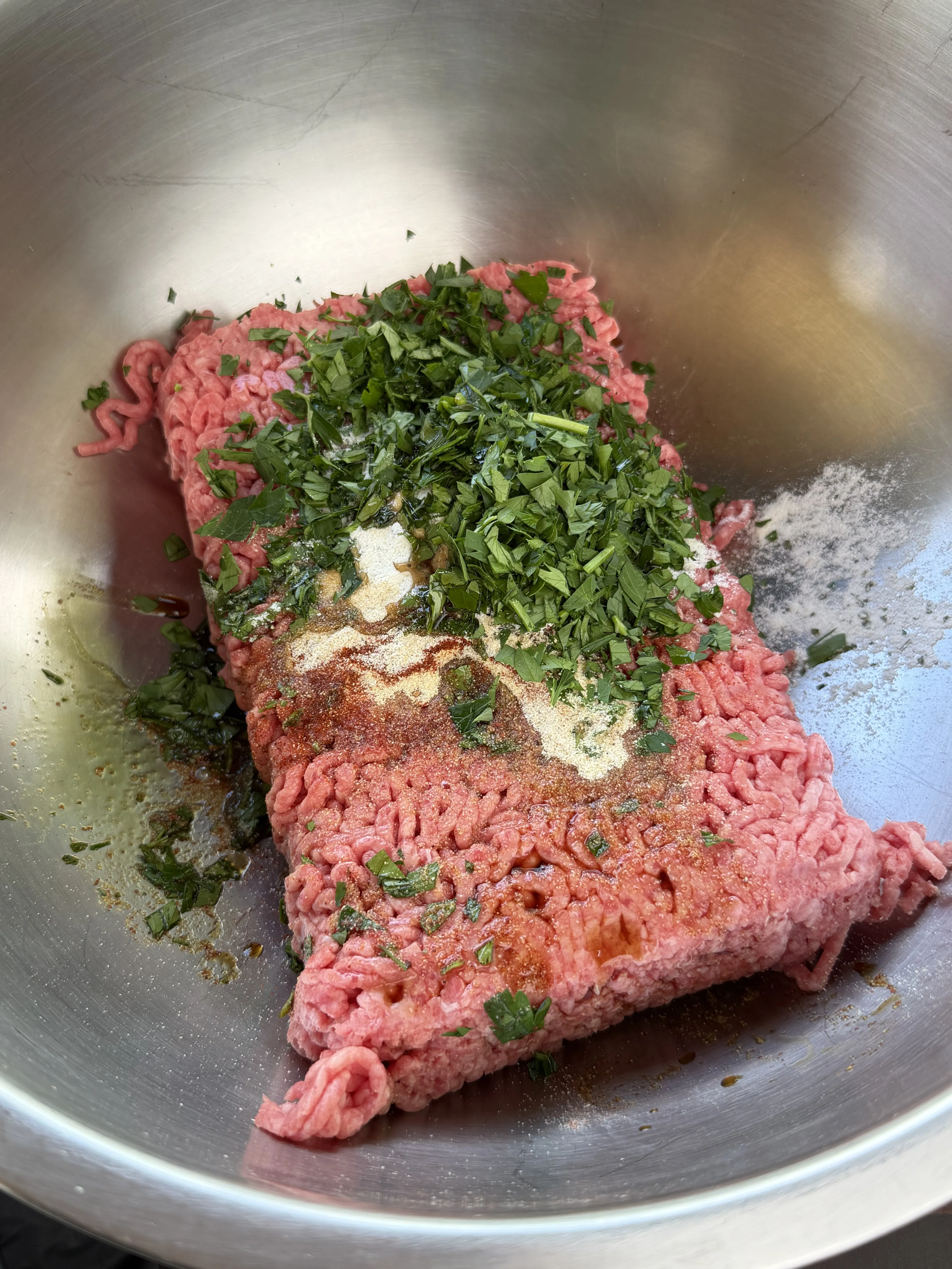 Ground chuck topped with parsley, spices, and Worcestershire before mixing