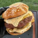Double-patty smoked bacon ranch stuffed burger with melted cheese and creamy sauce on a sesame seed brioche bun