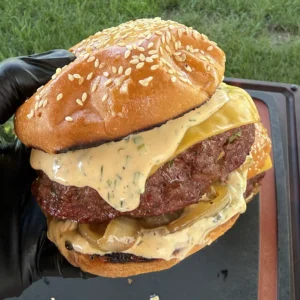 Double-patty smoked bacon ranch stuffed burger with melted cheese and creamy sauce on a sesame seed brioche bun