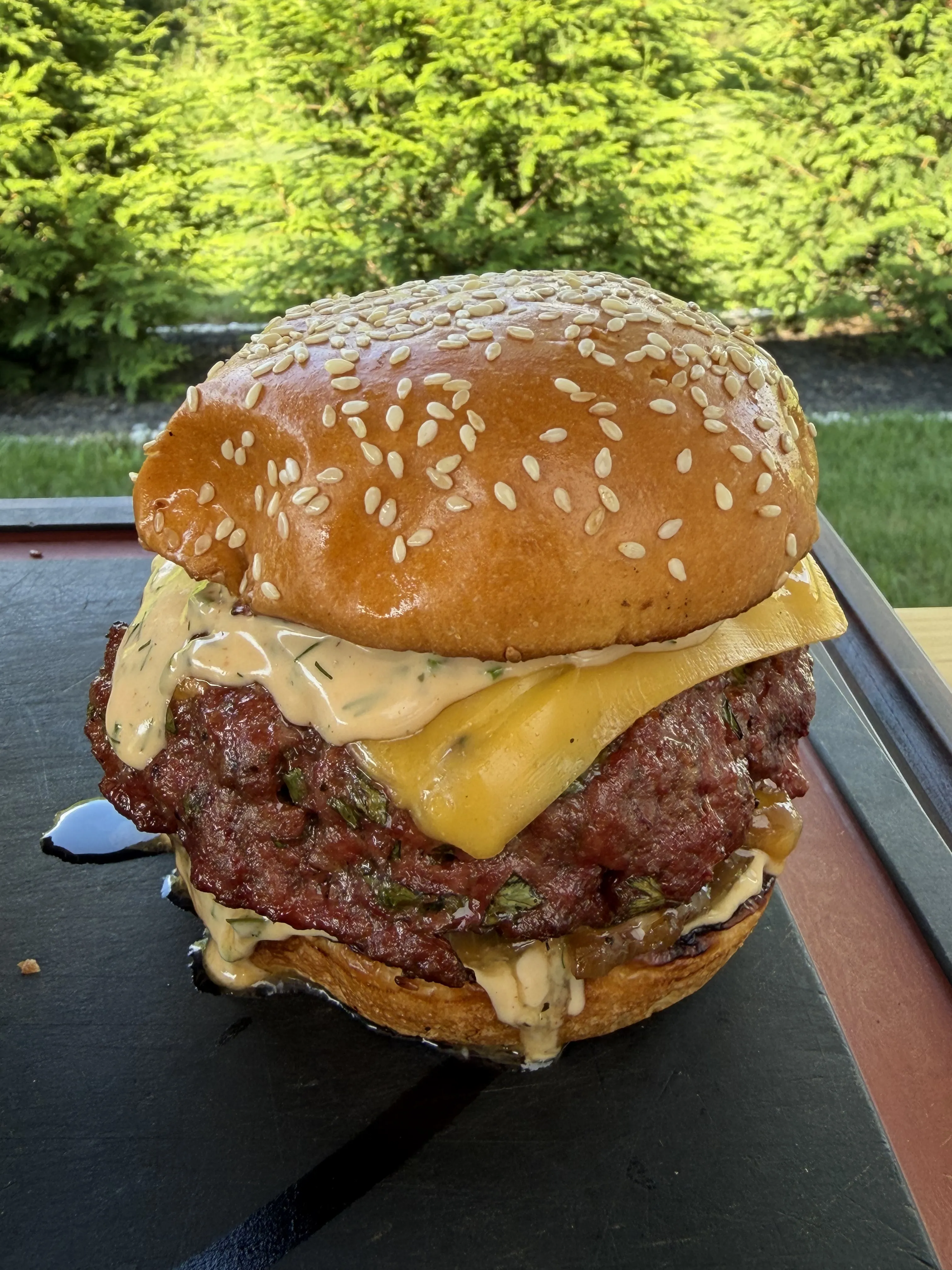 Smoked bacon ranch stuffed burger with melted cheddar and creamy sauce on a toasted sesame brioche bun
