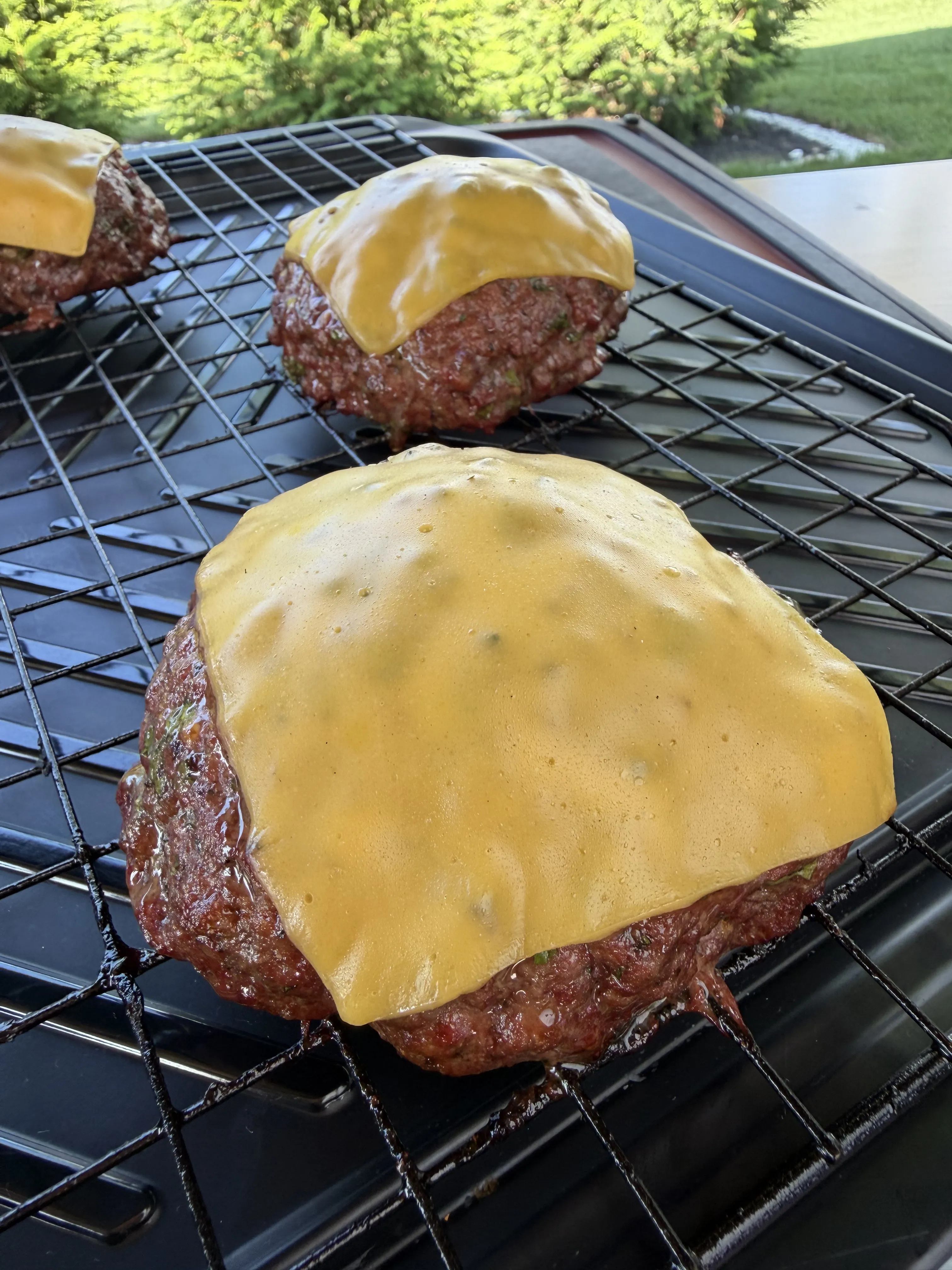 Stuffed smoked burgers with melting cheese on the smoker grates
