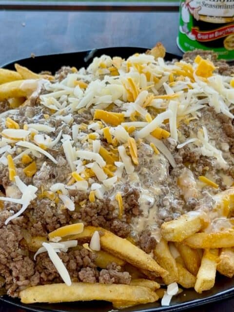 Bacon Cheeseburger Loaded Fries topped with ground beef, queso and shredded cheddar before baking