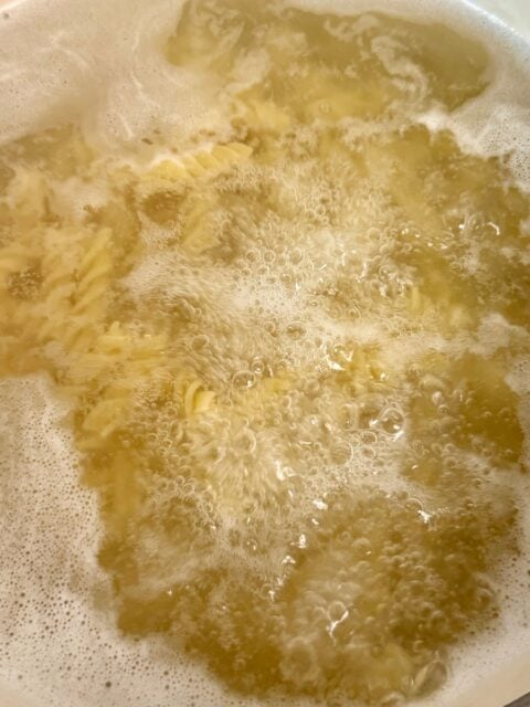 Rotini pasta cooking in salted boiling water for Mexican street corn pasta salad