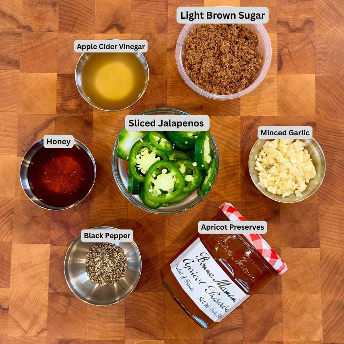 Ingredients for smoked cowboy candy including sliced jalapeños, apricot preserves, brown sugar, honey, apple cider vinegar, garlic and black pepper