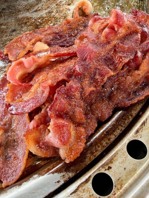 Crispy bacon cooking on the griddle for bacon cheeseburger sliders