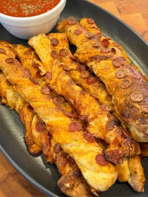 Pellet smoked pizza breadsticks served on a platter with warm pizza sauce for dipping