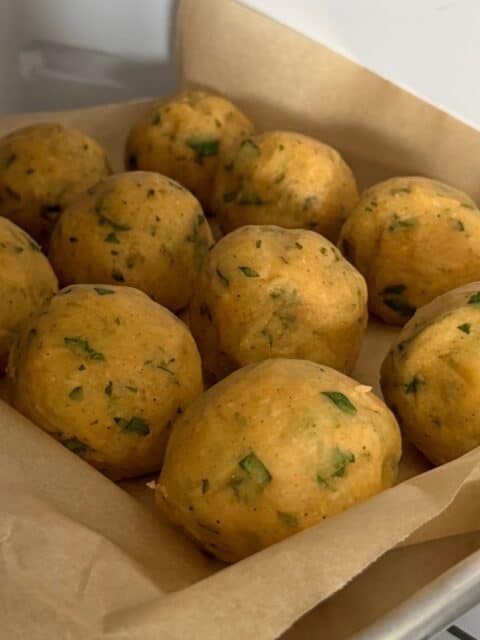 Formed Cajun cheese-stuffed potato croquettes chilling on a parchment-lined sheet pan
