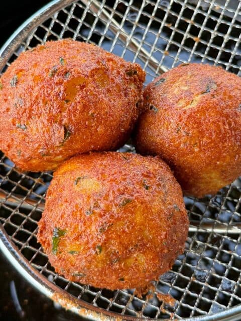 Cajun cheese-stuffed potato croquettes fried until golden in a fryer basket
