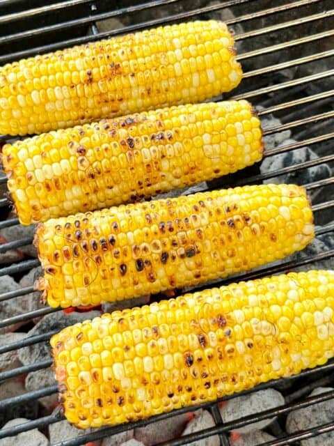 Fresh corn charred over a charcoal grill for Mexican street corn pasta salad