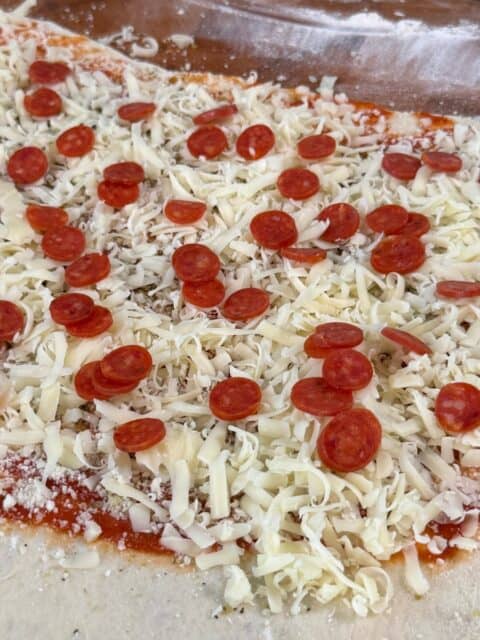 Pizza dough layered with pizza sauce, mozzarella, Parmesan, and mini pepperoni before folding