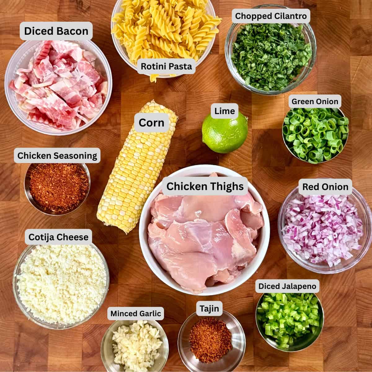 Mexican street corn pasta salad ingredients with chicken thighs, corn, rotini pasta, Cotija cheese, lime, cilantro, jalapeño, and red onion