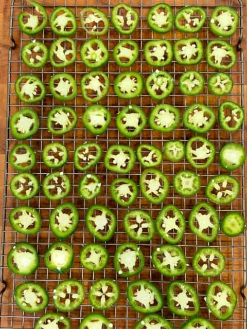 Sliced jalapeños arranged on a wire rack before smoking