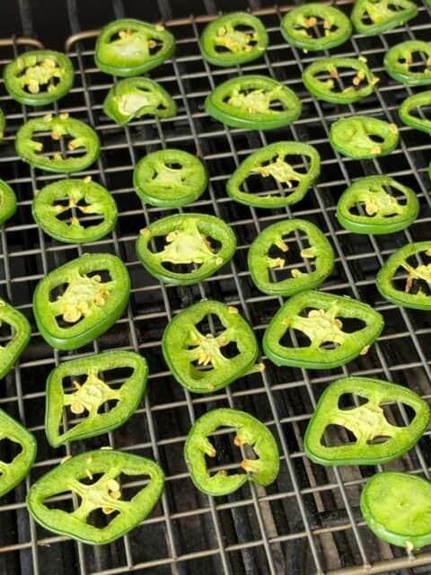 Jalapeño slices smoking on a wire rack at 250 degrees for smoked cowboy candy