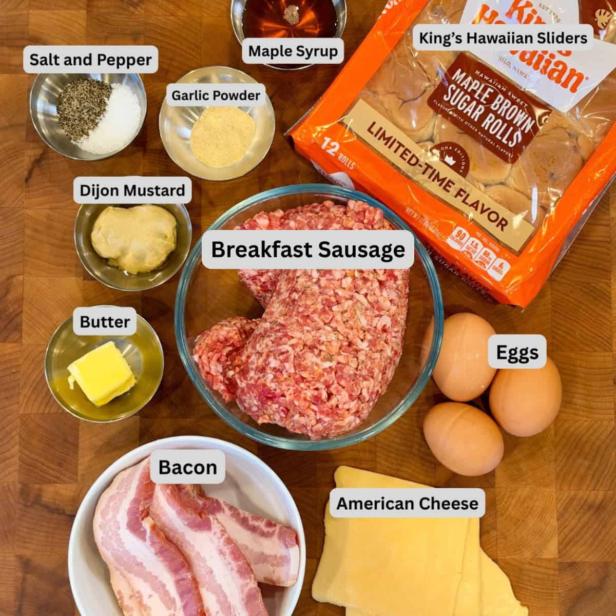 Ingredients for breakfast sliders: King's Hawaiian Maple Brown Sugar Rolls, breakfast sausage, bacon, eggs, American cheese, butter, maple syrup, Dijon mustard, garlic powder, salt, and black pepper.