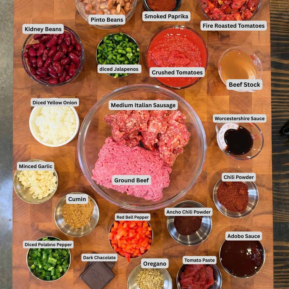 Key ingredients for Smoked Over the Top Chili including ground beef, Italian sausage, peppers, tomatoes, beans, beef stock, and seasonings.