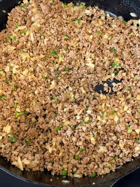 Browned ground chuck and Mexican chorizo returned to a Dutch oven with sautéed onions and jalapeños before adding the fire-roasted tomatoes.