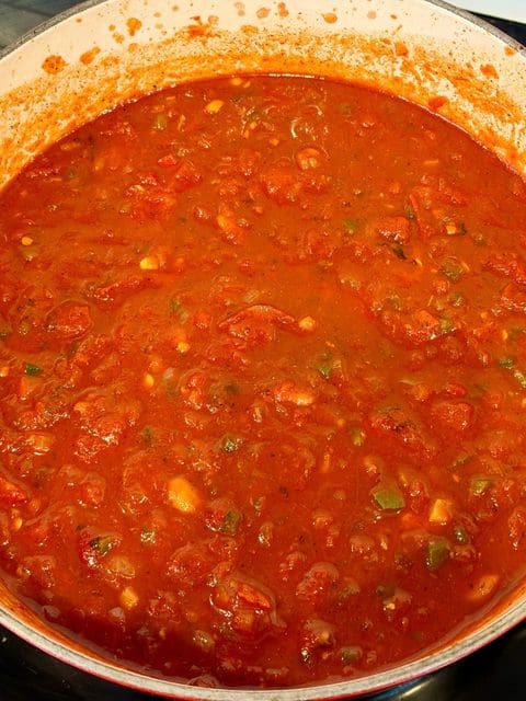 Smoked Over the Top Chili base with tomatoes, peppers, beans, and beef stock in a Dutch oven.