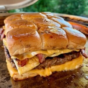 Easy Breakfast Sliders stacked with a griddled sausage patty, folded eggs, crispy bacon, and melted American cheese on King's Hawaiian Maple Brown Sugar Rolls.