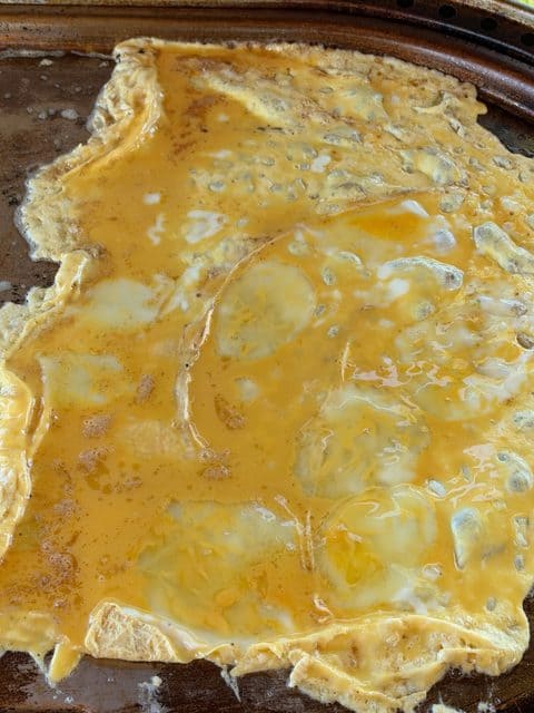 Eight beaten eggs gently folded into a large rectangular layer on a buttered flat-top griddle for Easy Breakfast Sliders.