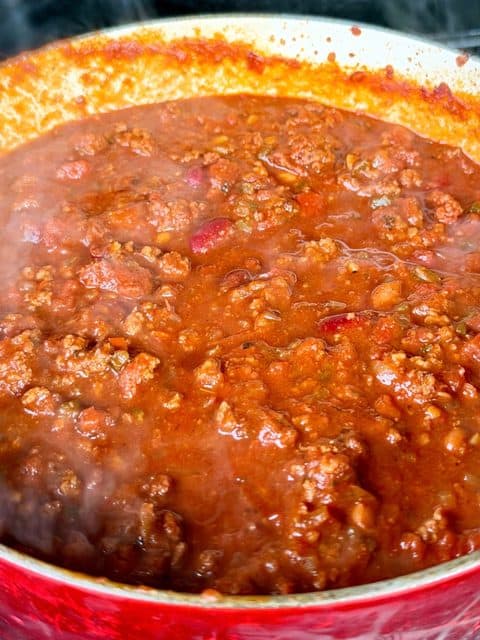 Dutch oven of over the top chili finishing on the smoker after adding the smoked meat.