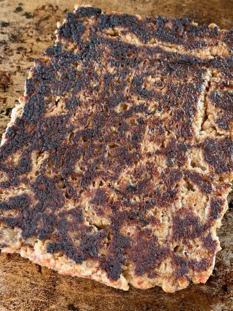 Oversized breakfast sausage patty with a browned crust cooking on a flat-top griddle for Easy Breakfast Sliders.