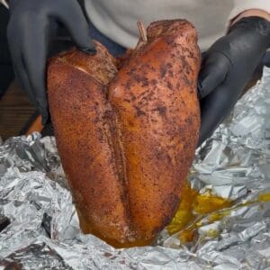 holding smoked turkey breast over a piece of aluminum foil.
