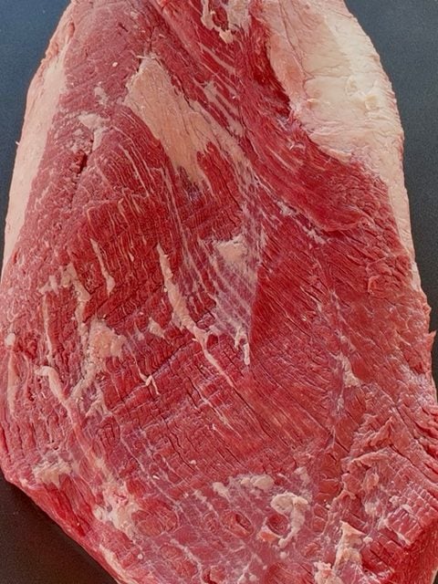 Raw whole packer beef brisket trimmed and shaped with excess fat and silver skin removed before seasoning and smoking.