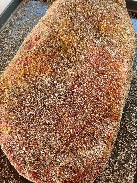 Trimmed beef brisket coated with yellow mustard, kosher salt, and coarse black pepper before smoking Texas-style brisket.
